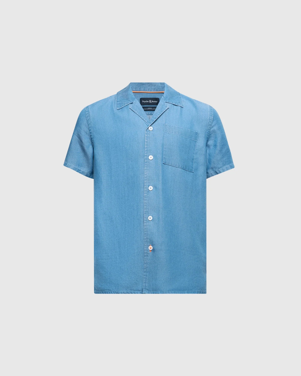 The KIDS KERVIN LIGHTWEIGHT DENIM WOVEN SHIRT by Psycho Bunny (Product ID: B0Q467F200) is a light blue, short-sleeve button-up shirt featuring a pointed collar and a left chest pocket with delicate bunny embroidery, shown on a plain white background.