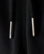 Close-up of black KIDS WILLIS STRETCH TENCEL SHORT featuring two drawstrings with silver metal tips engraved with "Bunny Psycho." The texture and slim fit highlight the intertwined threads, complemented by a subtle embroidered Bunny logo for playful sophistication.