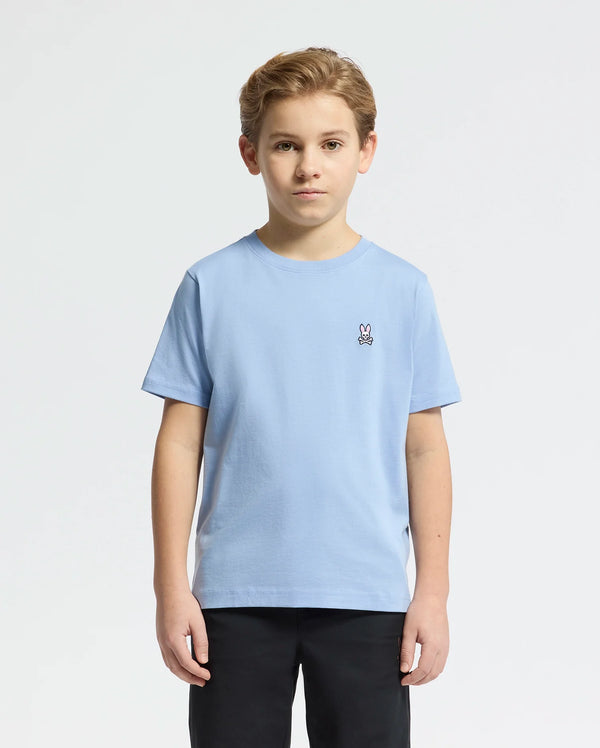 A young boy wears the Psycho Bunny KIDS CLASSIC CREW NECK TEE (B0U014B200) in light blue Pima cotton with an embroidered bunny logo on the upper left. He stands against a plain white background, facing the camera.