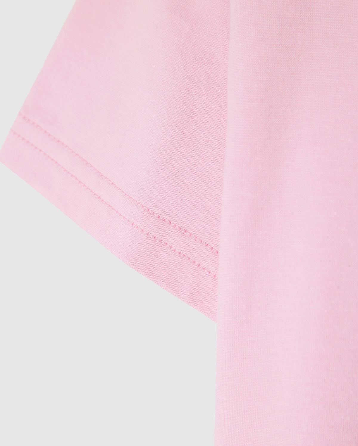 Close-up of the Psycho Bunny KIDS CLASSIC CREW NECK TEE - B0U014CRPC in pink, featuring visible sleeve stitching. Made from 100% Pima cotton for a soft and well-sewn finish, it's a high-quality choice perfect for back-to-school outfits.