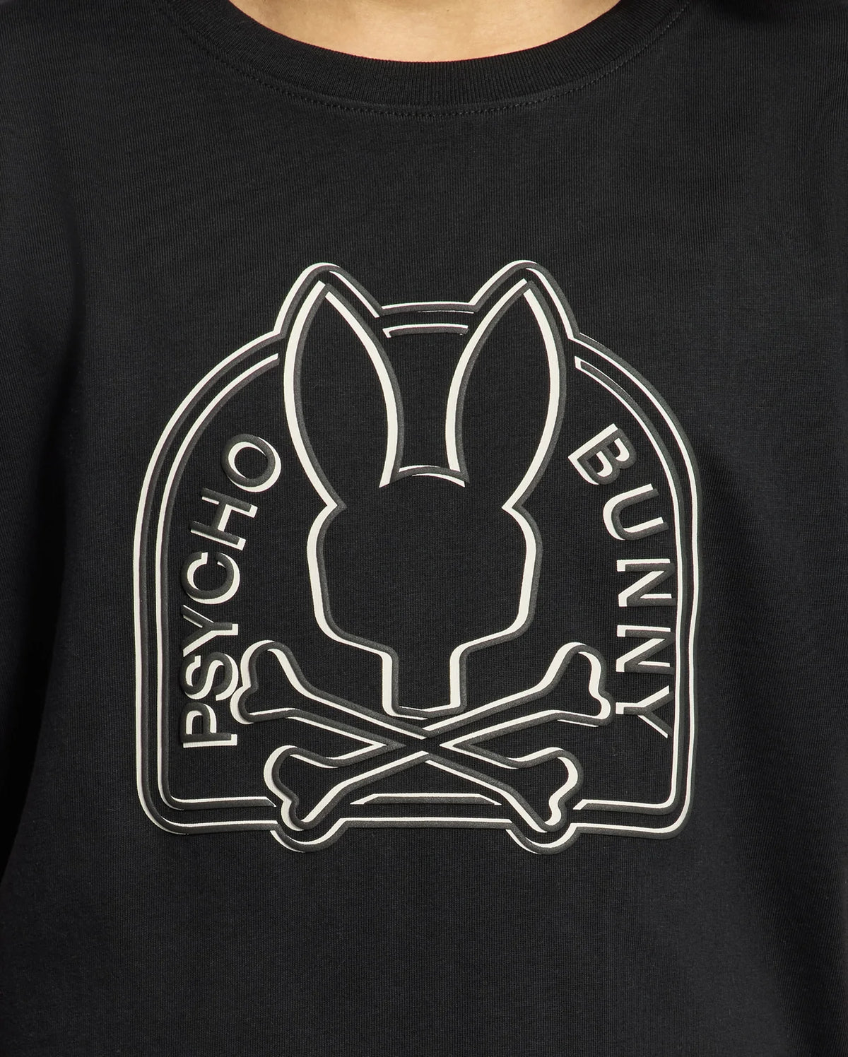 Close-up of the black KIDS MELBOURNE GRAPHIC TEE - B0U410F200 by Psycho Bunny, showcasing a logo with a stylized bunny head above crossed bones. Made from luxurious Peruvian Pima cotton, "Psycho Bunny" is elegantly written along the sides of the logo.
