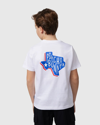 A person with short brown hair wears a white KIDS TEXAS CITY TEE (B0U553B2PC) by Psycho Bunny, showcasing a blue Texas-shaped graphic and "Psycho Bunny" in stylized text on the back. The luxurious Peruvian Pima cotton tee stands out against the plain light gray background.