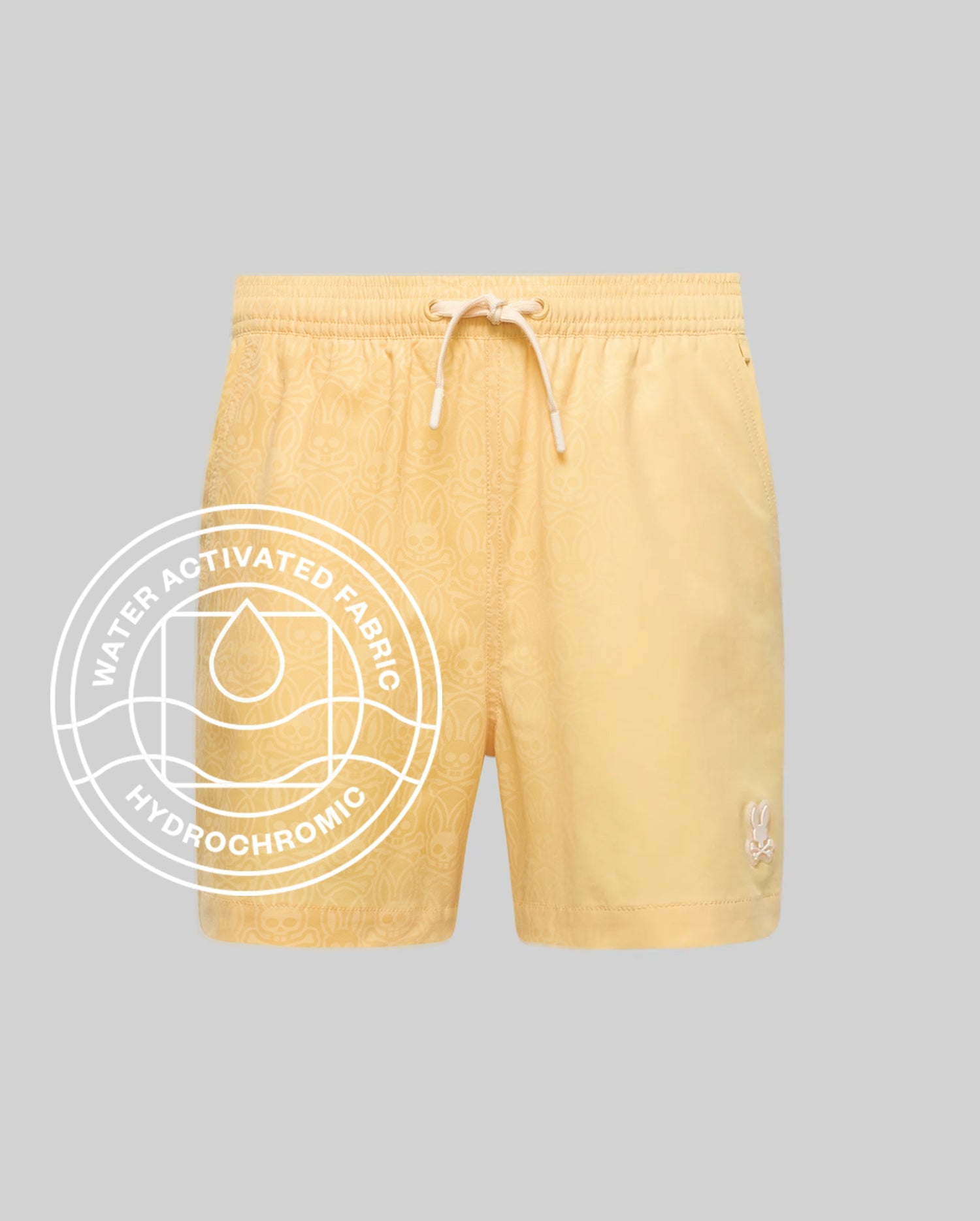 The Psycho Bunny MENS SAMOS HYDROCHROMIC PRINTED SWIM TRUNK (B6W453F200) features a light yellow shade, subtle bunny pattern, drawstring waist, white bunny logo on the left leg, and a "Water Activated Fabric Hydrochromic Technology" label.