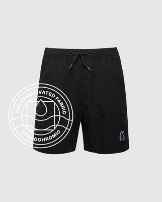 The KIDS SAMOS HYDROCHROMIC SWIM TRUNK by Psycho Bunny features quick-dry fabric, a subtle all-over pattern, elastic drawstring waistband, and an embroidered character. Overlay text: “Water Activated Fabric - Hydrochromic.”.