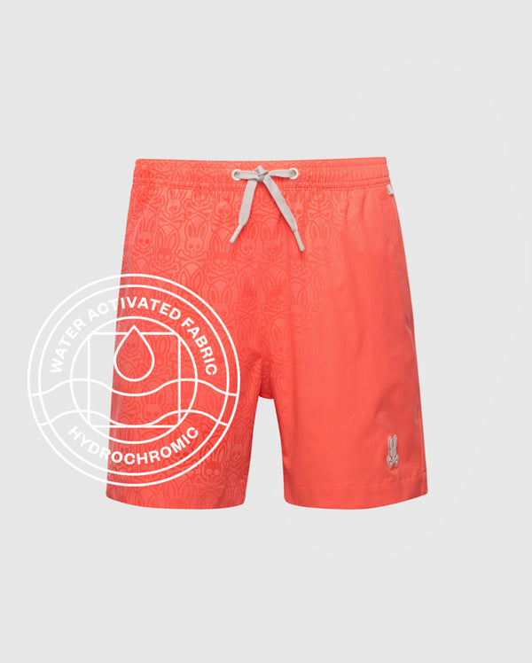 The Psycho Bunny KIDS SAMOS HYDROCHROMIC PRINTED SWIM TRUNK (B0W453F200) features coral quick-dry fabric, a subtle pattern, white drawstring, bunny logo on the left leg, and a water-activated hydrochromic emblem.
