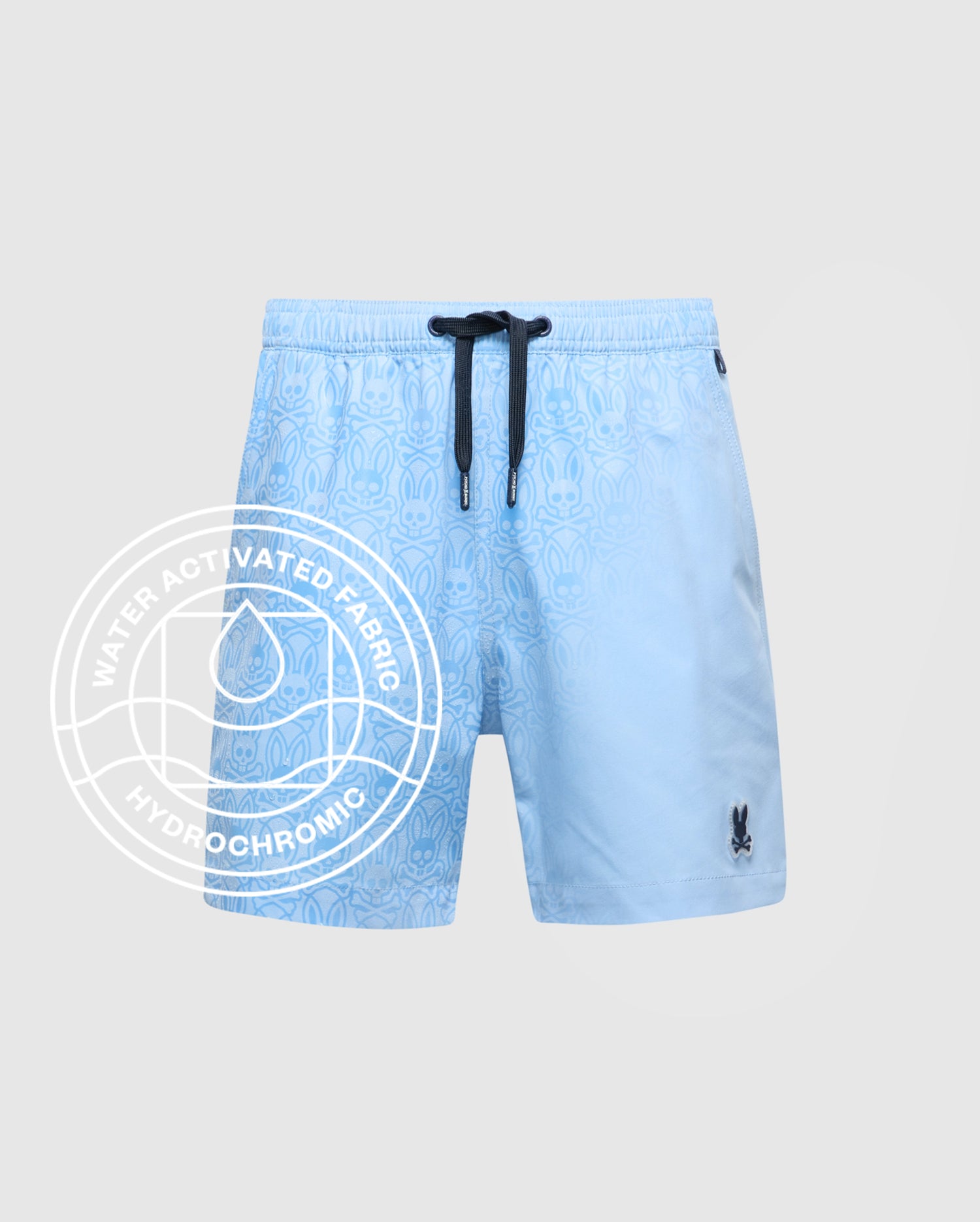 The KIDS SAMOS HYDROCHROMIC PRINTED SWIM TRUNK by Psycho Bunny features a light blue pattern, black drawstring, and bunny logo. Water-activated Hydrochromic fabric reveals hidden designs—ideal with your waterproof bag for pool days.