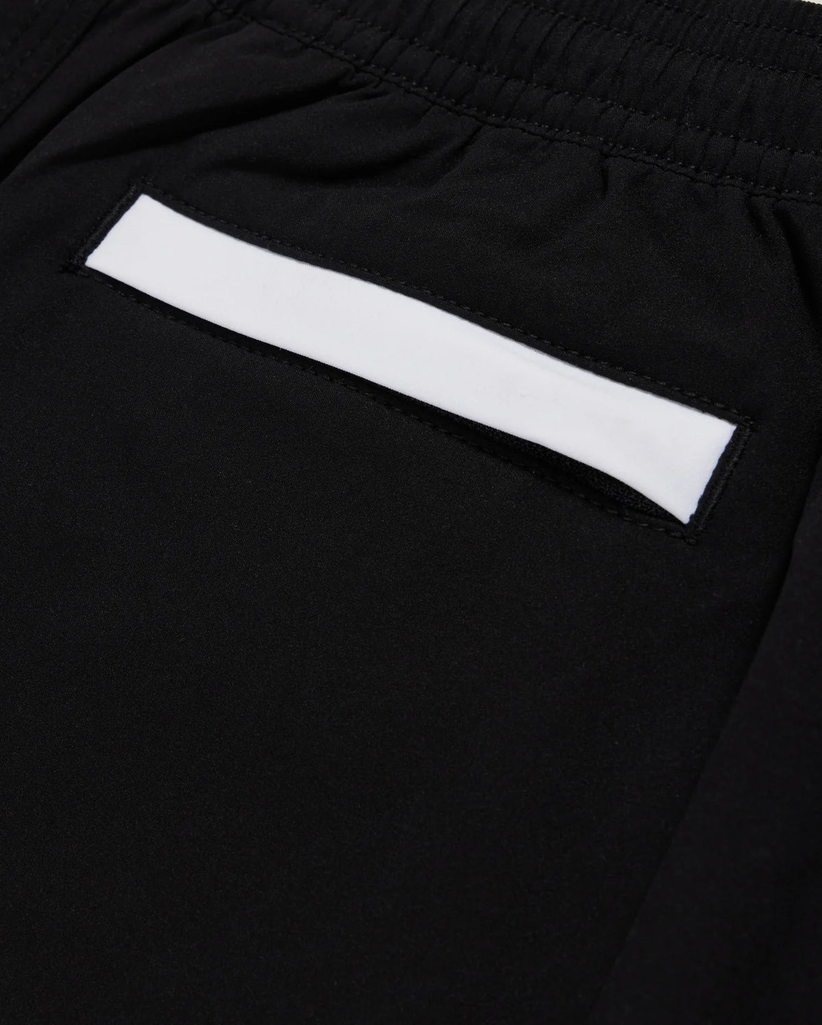 Close-up of a black fabric pocket on Psycho Bunny's KIDS PARKER HYDROCHROMIC SWIM TRUNK - B0W646C200, featuring an elastic waistband. The pocket highlights a white rectangular strip across its top edge and is made from quick-dry material.
