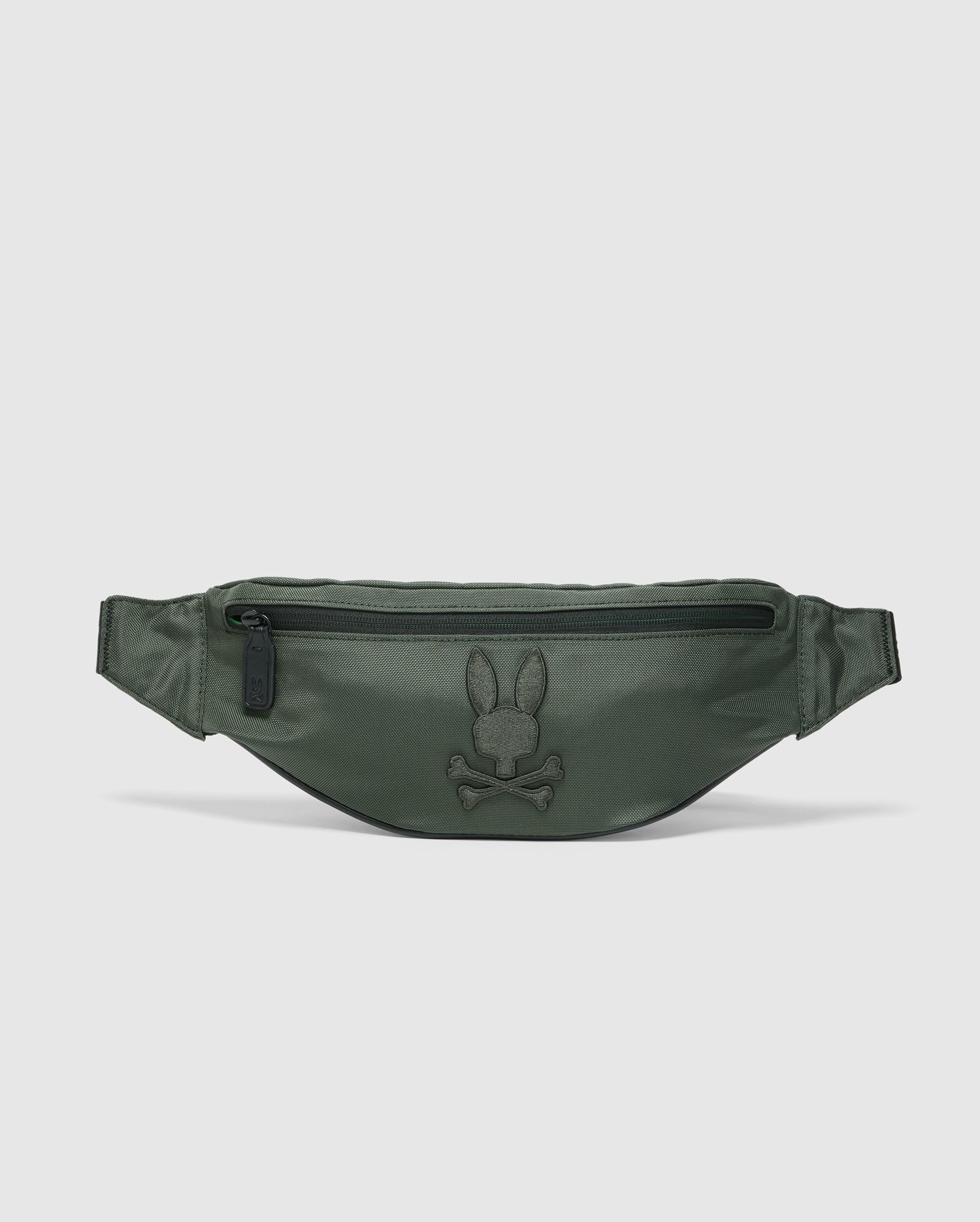 The Psycho Bunny MENS CROSS BODY BAG - B6A181E200 is a green travel bag for men, featuring a top zipper pocket and an embroidered rabbit and crossbones logo on the front. Made from smooth, semi-glossy nylon, it includes an adjustable strap for convenience.