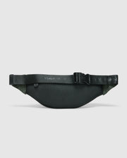 The Psycho Bunny MENS CROSS BODY BAG - B6A181E200 is a dark green textured nylon fanny pack featuring a black adjustable strap and a plastic buckle, displayed on a light gray background. It's perfect for men seeking convenience during travel.