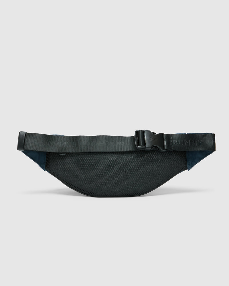 The Psycho Bunny MENS CROSS BODY BAG - B6A181E200, featuring a textured black surface, adjustable strap, and clasp buckle, is displayed against a white background, highlighting its minimalist and sleek design.