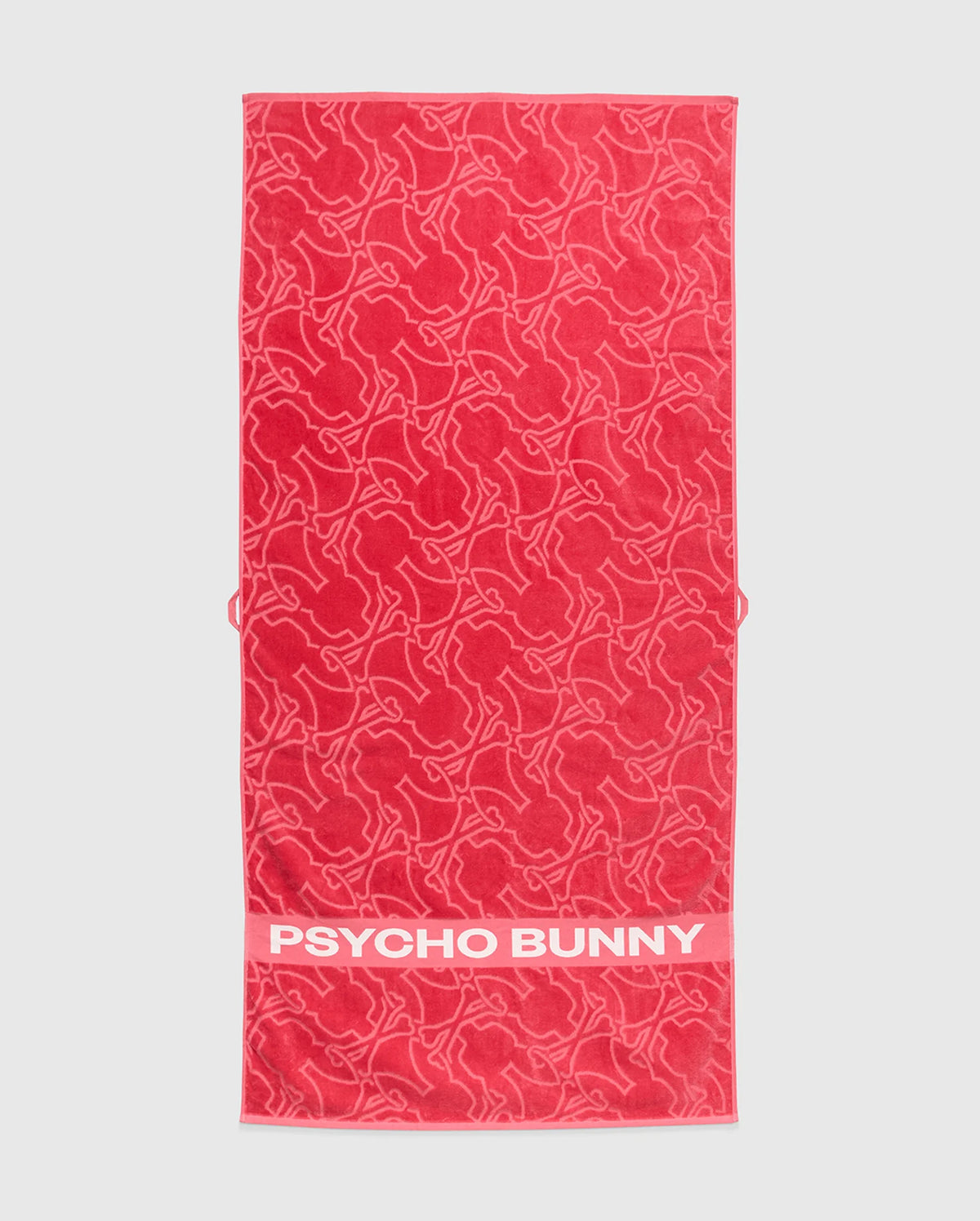 The Psycho Bunny TOWEL - B6A287F200 is a red terrycloth cotton towel with outlined bunny shapes and a solid band displaying bold white "PSYCHO BUNNY" text—ideal for fans of premium style.