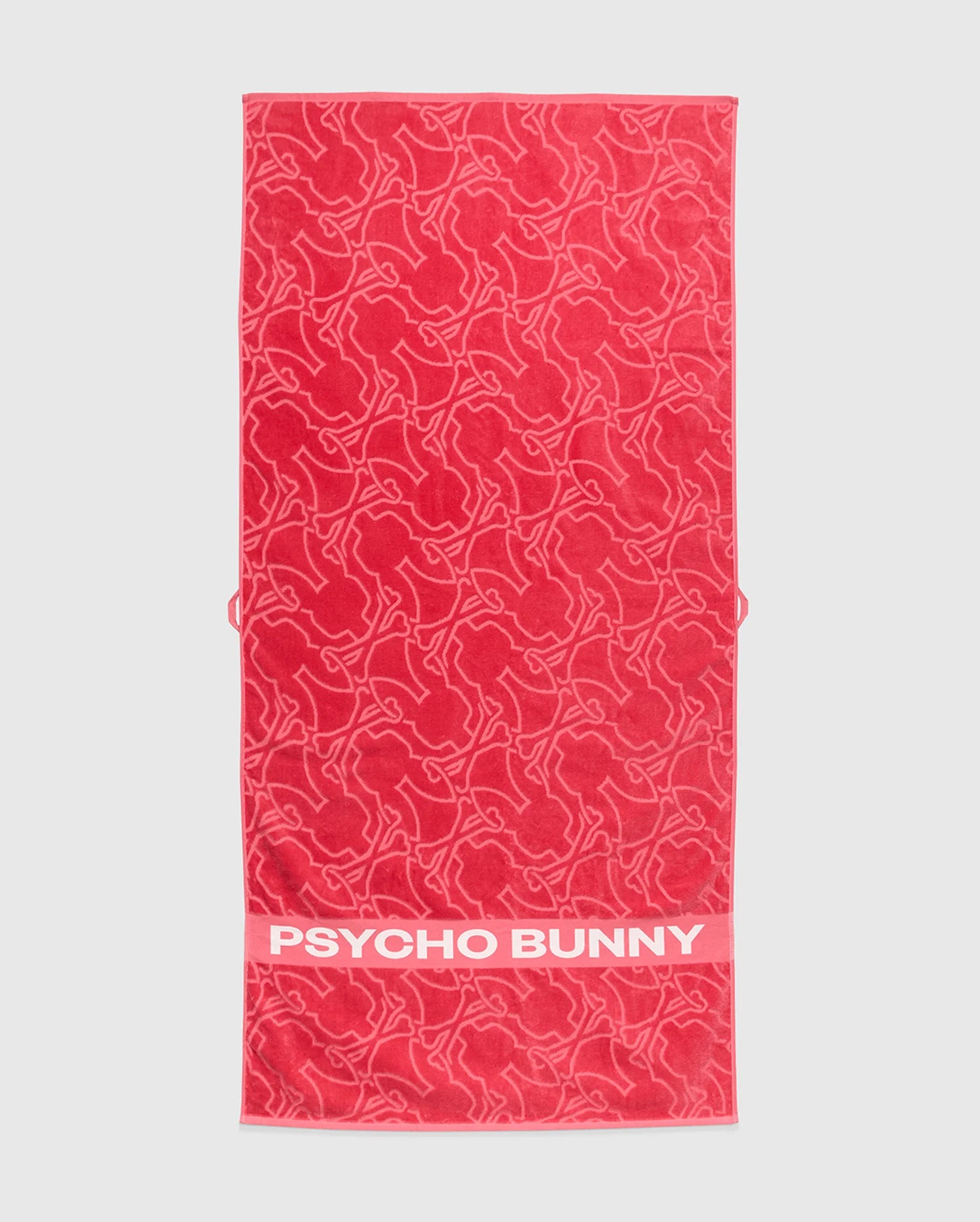 The Psycho Bunny TOWEL - B6A287F200 is a red terrycloth cotton towel with outlined bunny shapes and a solid band displaying bold white "PSYCHO BUNNY" text—ideal for fans of premium style.