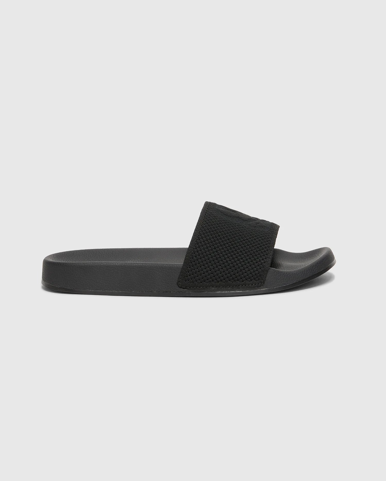 The Psycho Bunny MENS KNIT SLIDES - B6A474F200 are black slide sandals with textured straps, flat soles, and molded footbeds for comfort. Displayed against a white background, they feature an open toe design.