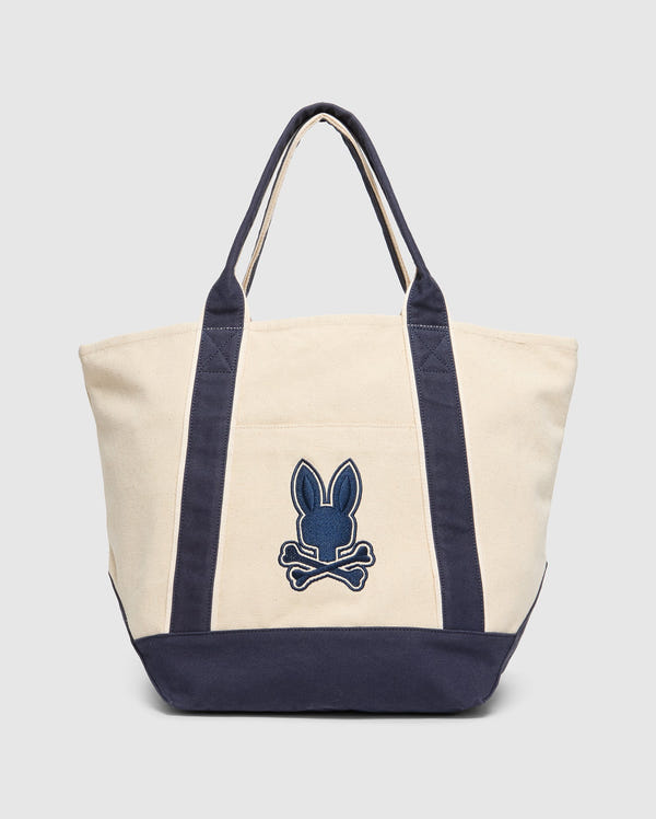 The MENS GRAPHIC TOTE - B6A563F200 from Psycho Bunny is a beige, durable bag featuring dark blue handles and base. A bold blue rabbit head with crossbones embellishes the front, emphasizing its functionality-first design.