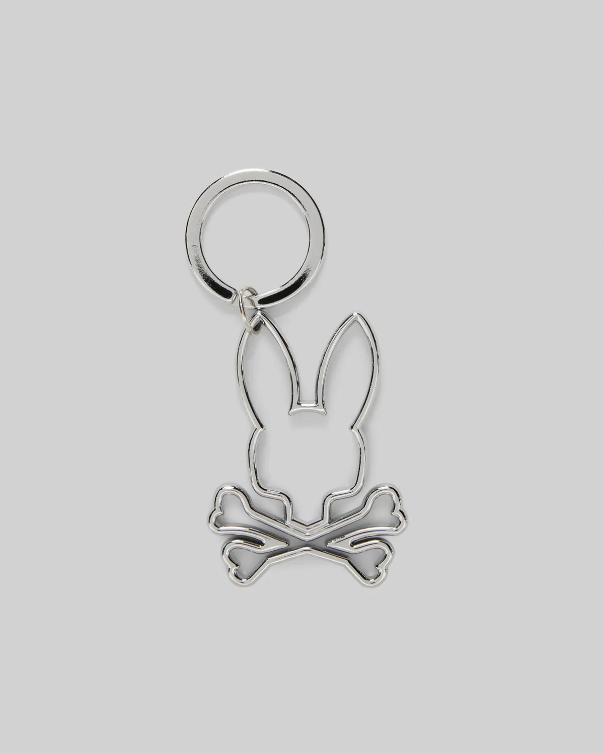 The Psycho Bunny MENS OUTLINE BUNNY KEYCHAIN (B6A565E200) is a durable silver accessory featuring a rabbit head over crossed bones, crafted from zinc alloy and set on a plain gray background.