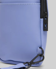 Close-up of the MENS RUBBERIZED CROSSBODY - B6A635F200 by Psycho Bunny in light purple polyester, featuring black zipper hardware, a bunny logo pull, and a matching adjustable strap with a black clasp attached to the bottom corner.