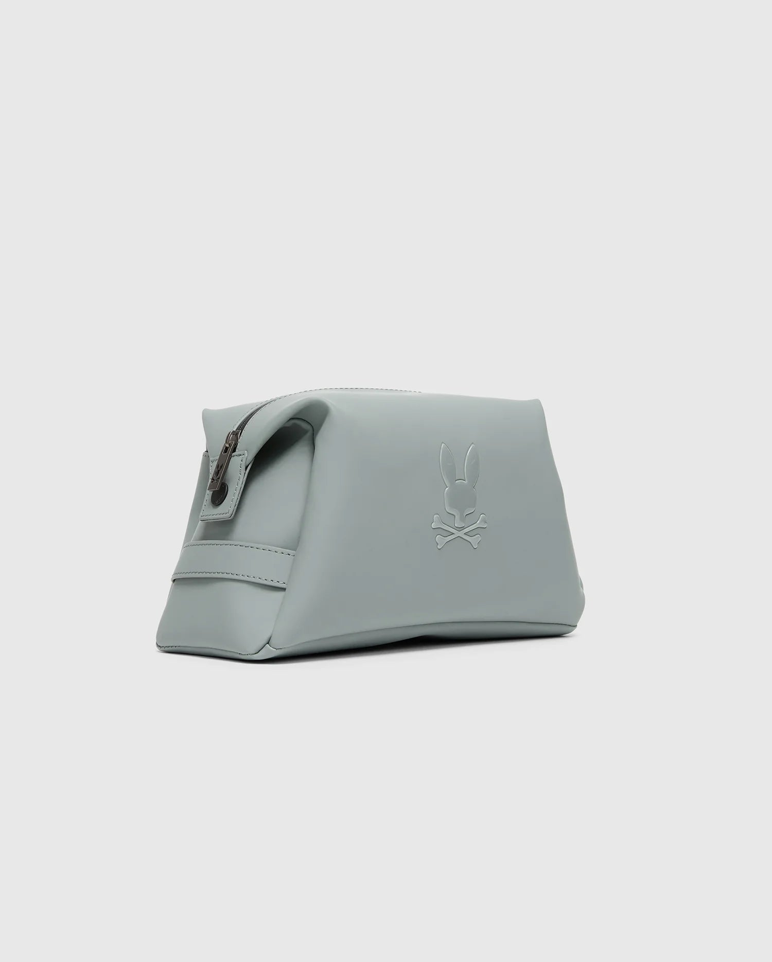 The Psycho Bunny MENS RUBBERIZED TOILETRY KIT (B6A189E200) is a light gray polyester bag with a zipper and embossed rabbit and crossbones logo—stylish, practical, and perfect for organizing essentials on the go.