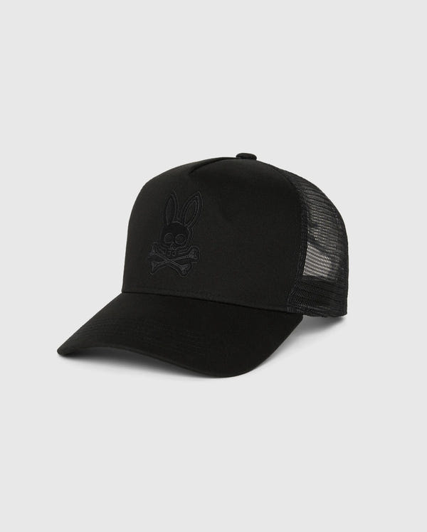 The MENS MALTON TRUCKER CAP - B6A797D200 by Psycho Bunny features a black mesh back and an embroidered bunny logo with crossbones on the front panel, crafted from cotton for standout appeal against a neutral background.