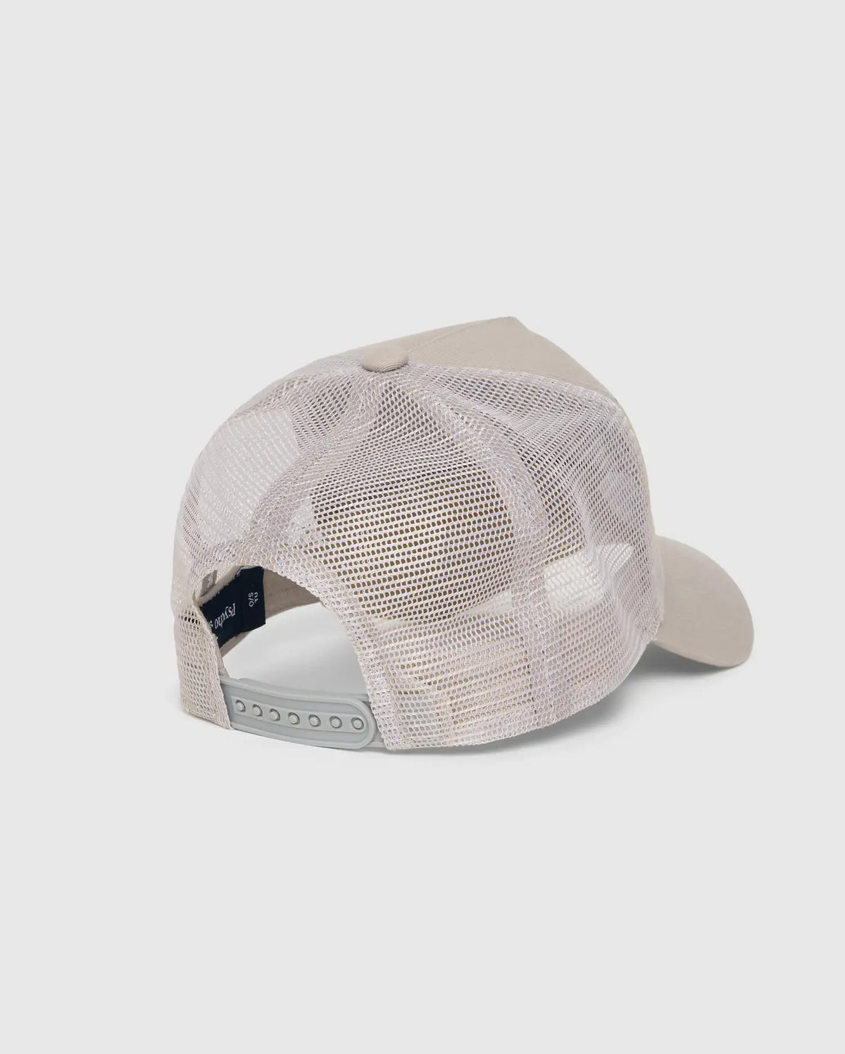 The MENS MALTON TRUCKER CAP - B6A797D200 by Psycho Bunny is displayed from behind, highlighting its adjustable snap closure. The beige cap boasts a 100% cotton solid front panel, mesh ventilation, and a curved brim against a plain light gray background.
