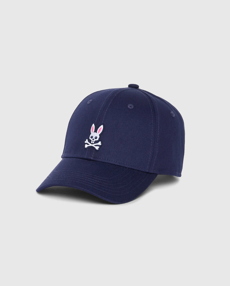 Product Description: The MENS CLASSIC BASEBALL CAP - B6A816A1HT by Psycho Bunny is a classic navy blue six-panel cotton twill cap, showcasing a pink-eared white bunny logo above a crossbones design embroidered on the front against a light gray background.