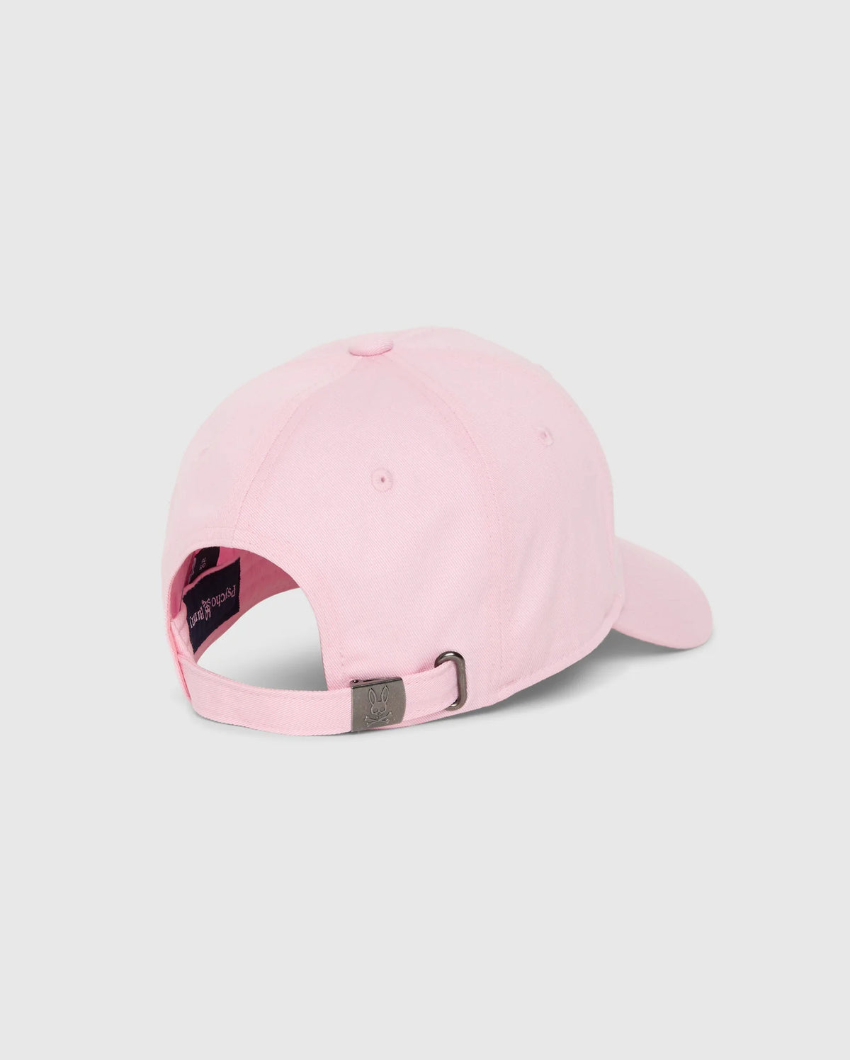 The MENS CLASSIC BASEBALL CAP - B6A816A1HT by Psycho Bunny is showcased from the back, highlighting its light pink hue crafted from six-panel cotton twill. This classic design includes an adjustable strap with a metal buckle for personalized fit. The inner lining near the strap is in a darker shade, offering a striking contrast to the pastel pink fabric and featuring an embroidered Bunny logo.