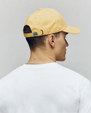 A person is shown from behind, facing away from the camera, wearing a Psycho Bunny MENS CLASSIC BASEBALL CAP - B6A816F200 in yellow and a white T-shirt against a neutral background.