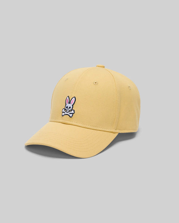 The Psycho Bunny MENS CLASSIC BASEBALL CAP - B6A816F200 is a yellow recycled polyester cap with a curved brim, adjustable fit, and an embroidered pink bunny above white crossed bones on the front. Shown on a plain gray background.