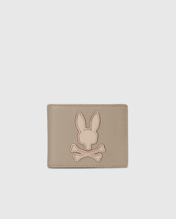 The MENS LEATHER WALLET - B6A868D200 by Psycho Bunny features a stitched bunny head over crossed bones on its light gray front. Its premium leather and unique design make it a luxurious accessory for the discerning.