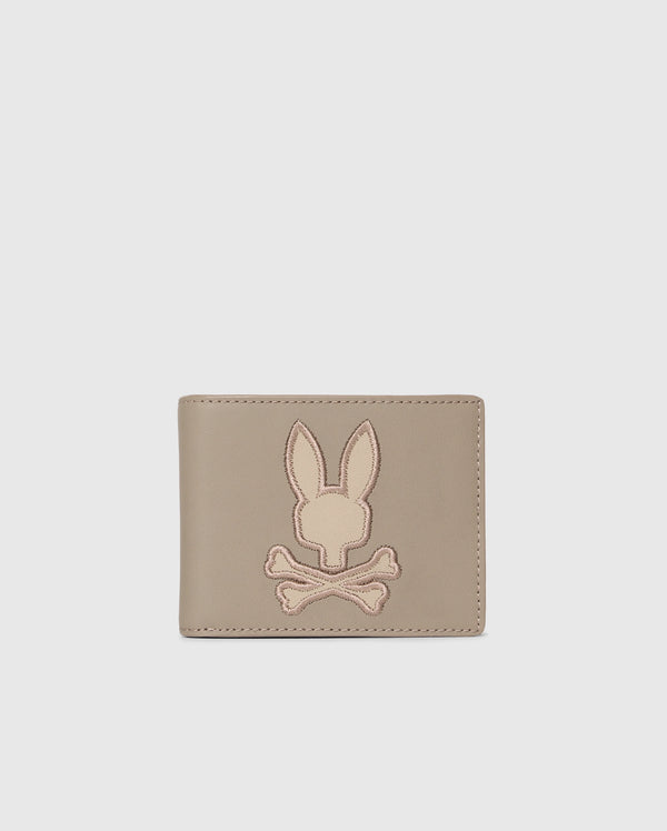 The MENS LEATHER WALLET - B6A868D200 by Psycho Bunny features a stitched bunny head over crossed bones on its light gray front. Its premium leather and unique design make it a luxurious accessory for the discerning.