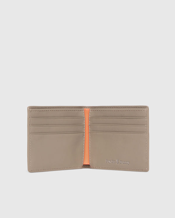 The MENS LEATHER WALLET - B6A868D200 by Psycho Bunny is open, showing six card slots with an orange center divider. The brand name is elegantly embossed in silver on the bottom right corner of this luxurious beige wallet's interior.