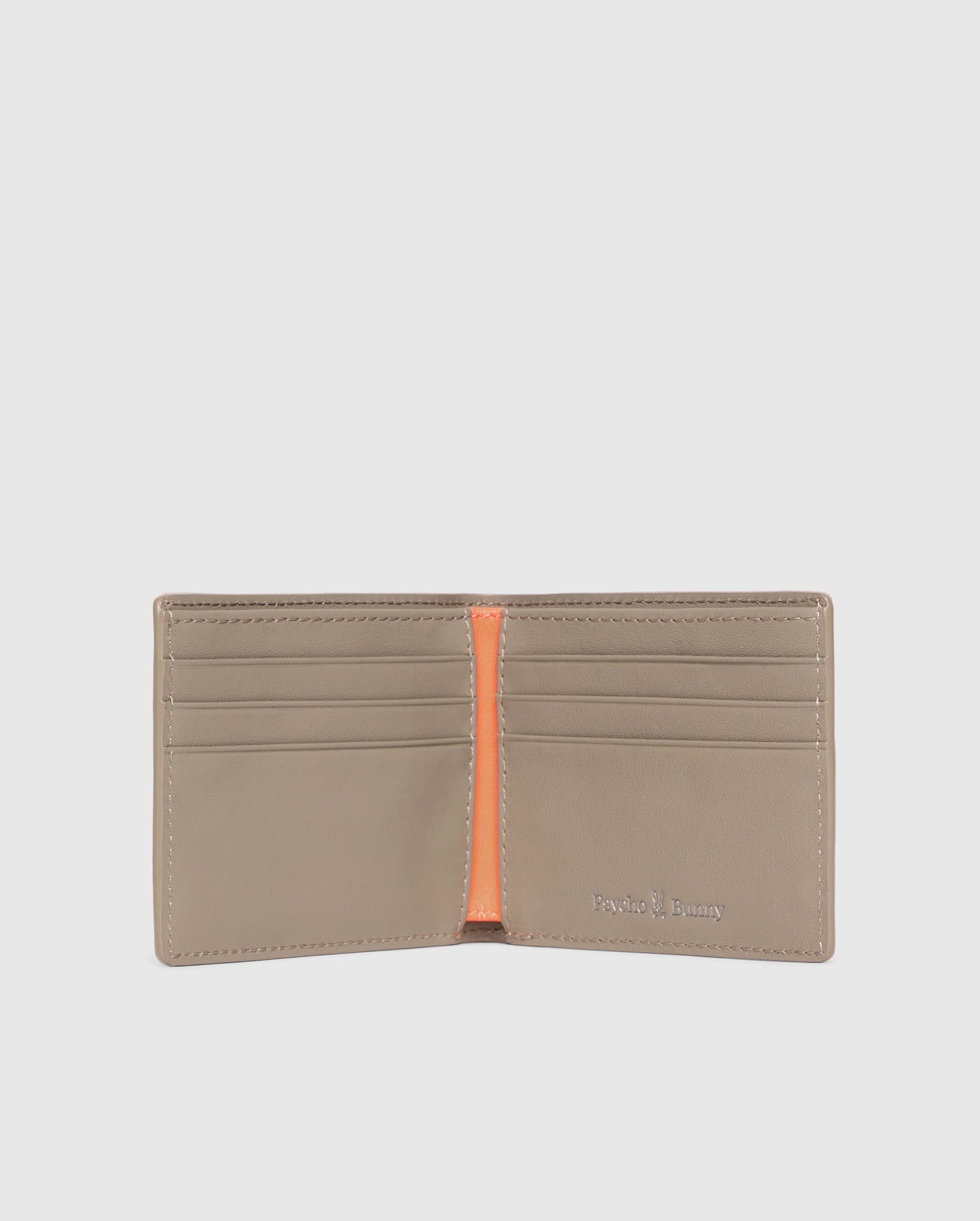 The MENS LEATHER WALLET - B6A868D200 by Psycho Bunny is open, showing six card slots with an orange center divider. The brand name is elegantly embossed in silver on the bottom right corner of this luxurious beige wallet's interior.