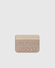 Beige leather card holder from Psycho Bunny with "PSYCHO BUNNY" in pink embroidery. The MENS WORDMARK LEATHER CARD CASE - B6A869D200 features a minimalist design on a pure white background, highlighting its premium leather craftsmanship.