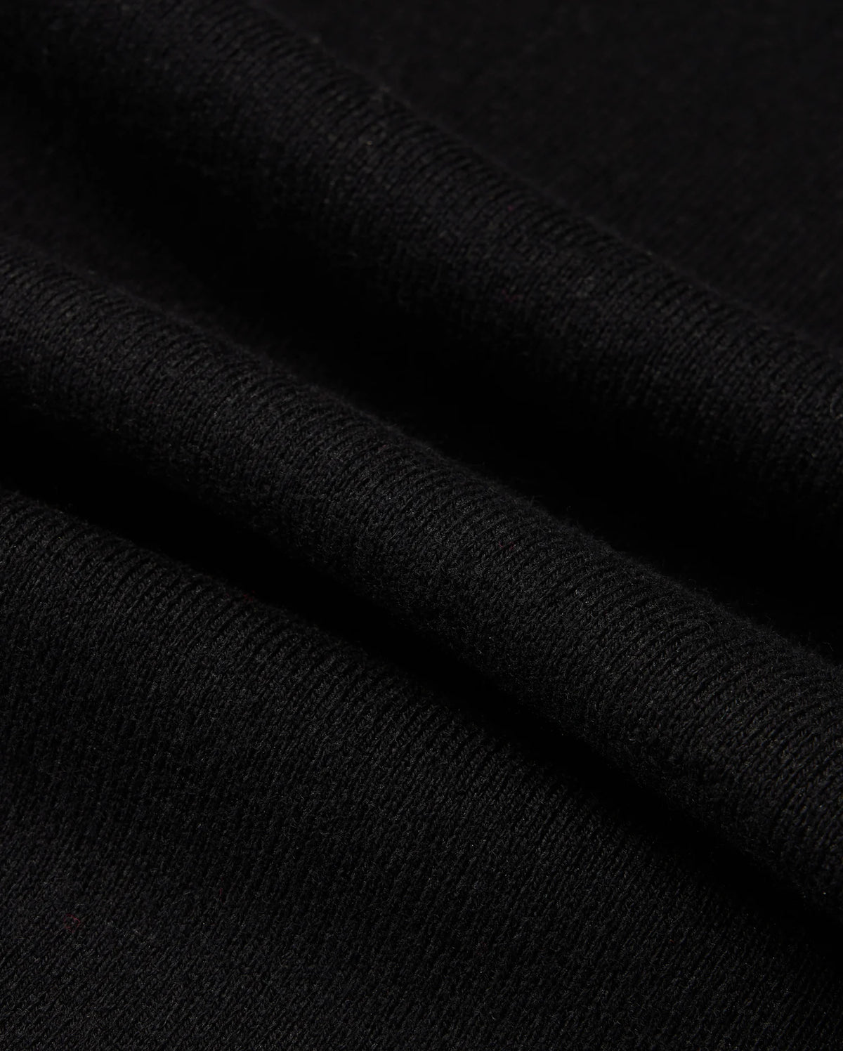 Close-up of the Psycho Bunny MENS MONROE TWILL PATCH SCARF - B6A892D200, showcasing its soft, smooth texture and fine weave. This luxurious black scarf features slight folds and shadows, highlighting its gentle drape and high-quality cotton wool blend.