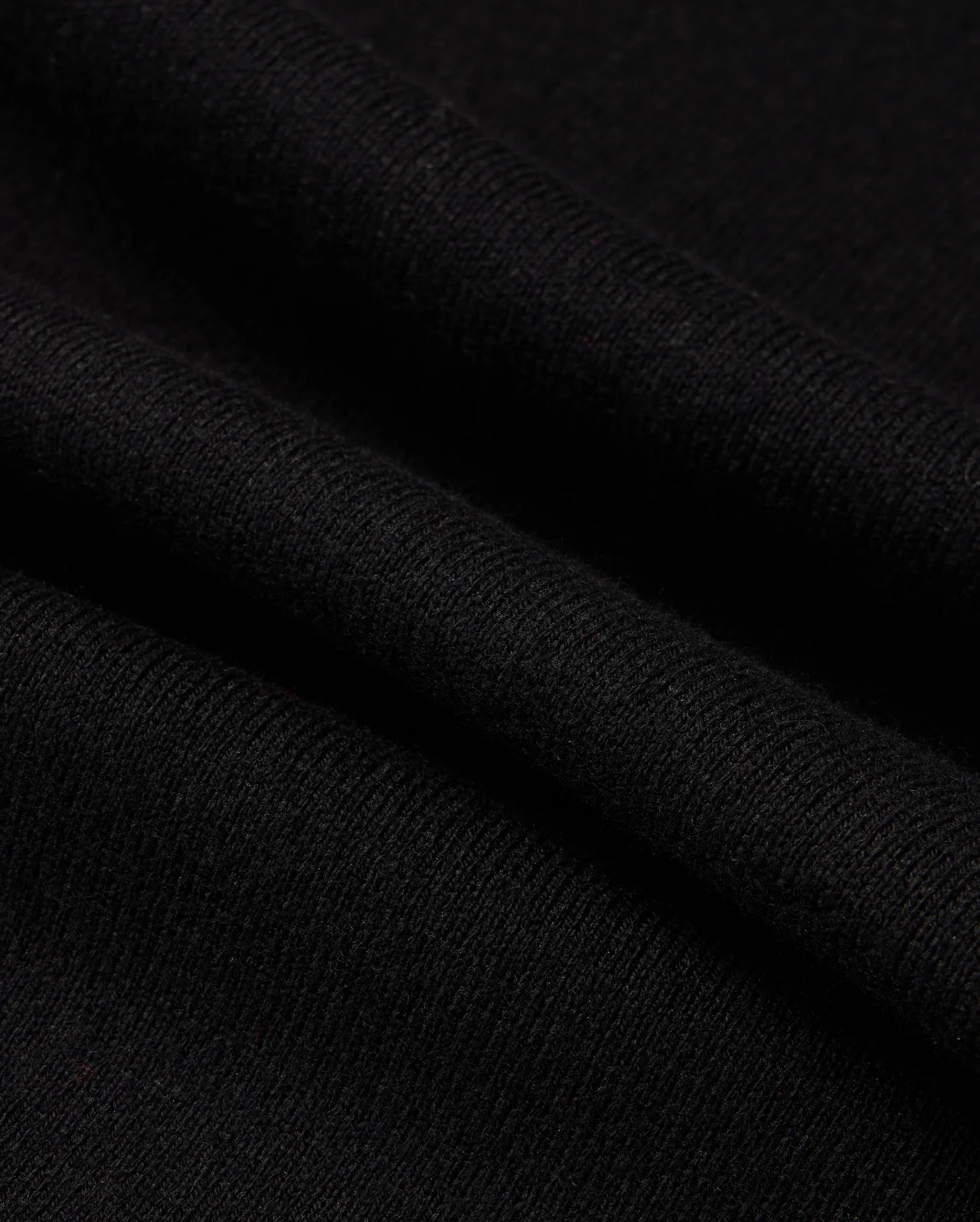 Close-up of the Psycho Bunny MENS MONROE TWILL PATCH SCARF - B6A892D200, showcasing its soft, smooth texture and fine weave. This luxurious black scarf features slight folds and shadows, highlighting its gentle drape and high-quality cotton wool blend.