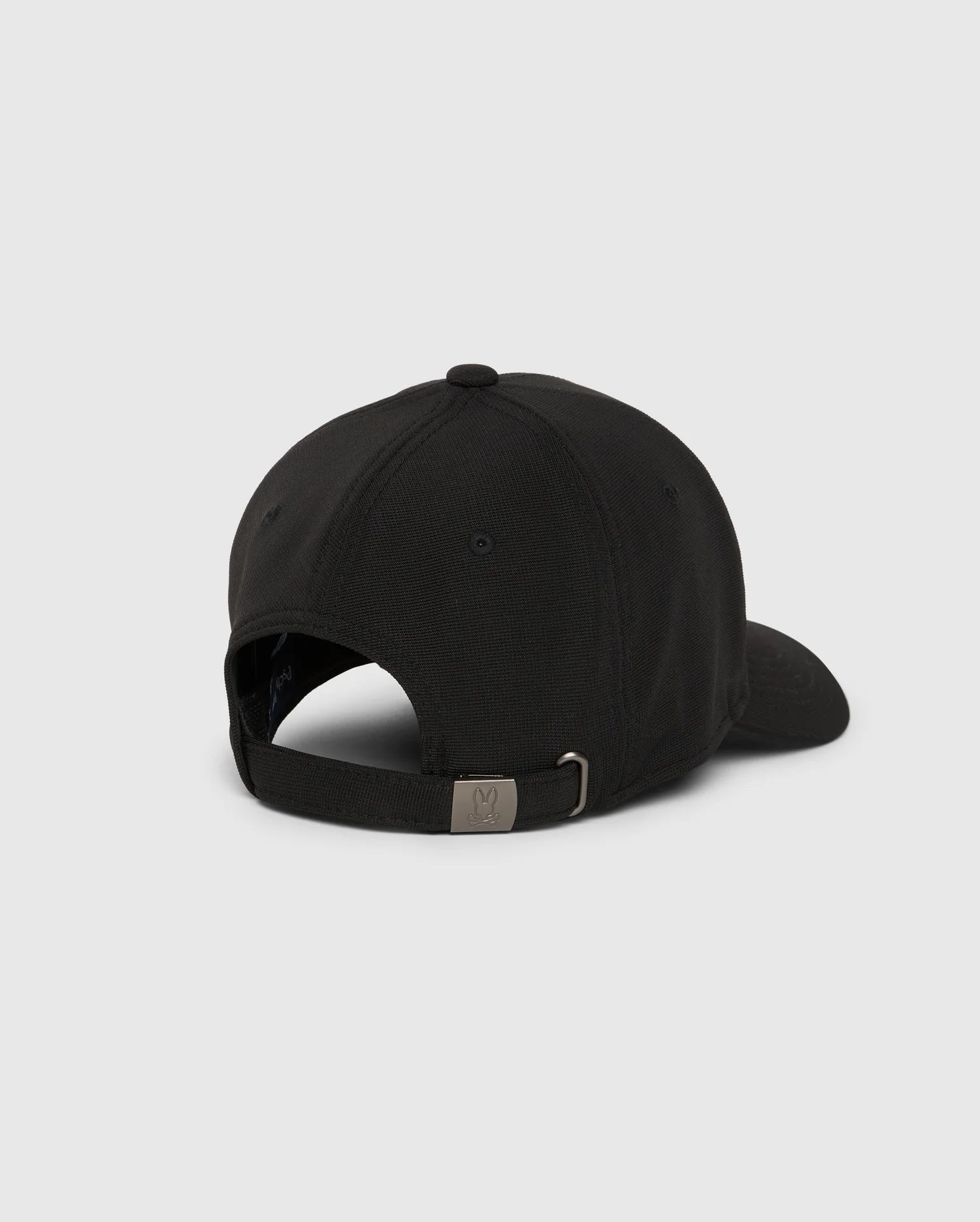 A MENS JAMES PREMIUM BASEBALL CAP - B6A953D200 from Psycho Bunny is displayed from the back, showcasing an adjustable strap with a metal buckle. Made of a subtly textured polyester spandex fabric, the cap includes a curved brim and features an embroidered Psycho Bunny logo that adds a playful element against its light gray background.