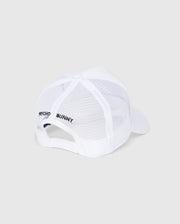 The MENS BUNNY PATCH TRUCKER CAP - B6A965C200 by Psycho Bunny is a white mesh baseball cap with a solid brim and adjustable strap. It features "Psycho Bunny" text on the side for a sporty, casual trucker hat style.