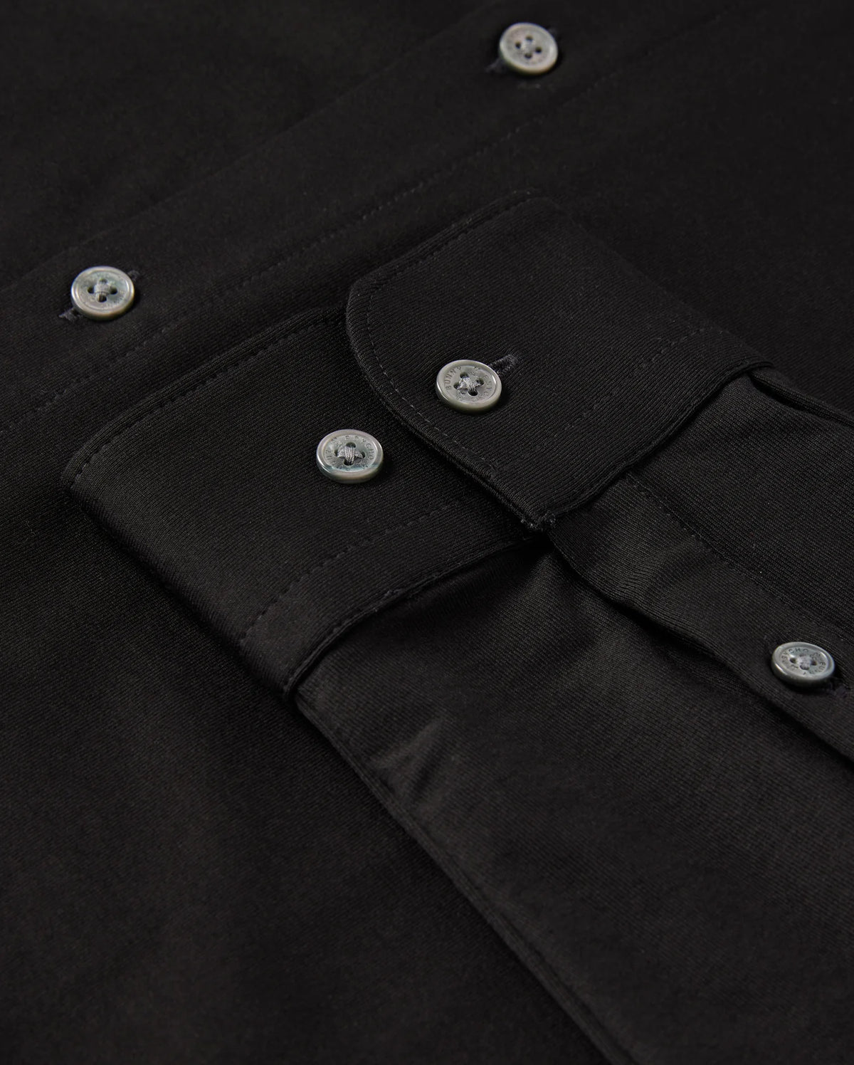 Close-up of the MENS ARTHUR JERSEY SHIRT - B6C748D200 by Psycho Bunny, made from stretch Pima cotton with a detailed view of buttons and stitching. The image prominently features four silver buttons and a pocket flap with a similar button, showcasing the texture and craftsmanship of the jersey fabric.