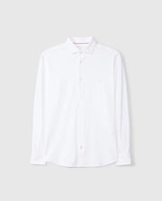 The MENS ARTHUR JERSEY SHIRT - B6C748D200, by Psycho Bunny, is a white long-sleeve button-up dress shirt crafted from premium stretch Pima cotton. Displayed against a light gray background, this shirt features a classic collar and boasts a clean, minimalist design with the brand logo subtly embroidered on the left chest.