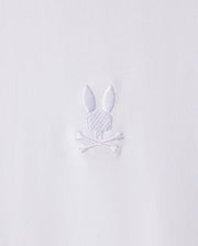 White embroidery on stretch Pima cotton fabric depicts a stylized rabbit head with long ears above a pair of crossed bones. The design, featured on the Psycho Bunny Men's Arthur Jersey Shirt (B6C748D200), is simple and monochromatic.
