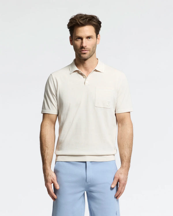 A man stands against a plain background wearing the Psycho Bunny MENS LONGFORD FINE KNIT POLO (B6E500F200) with light blue pants. With short, styled hair, he maintains a neutral expression while facing the camera.