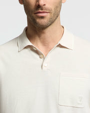 A man wears a Psycho Bunny MENS LONGFORD FINE KNIT POLO in light cotton, featuring a collar and left chest pocket with subtle embroidered Bunny. The plain white design highlights his partially visible face.