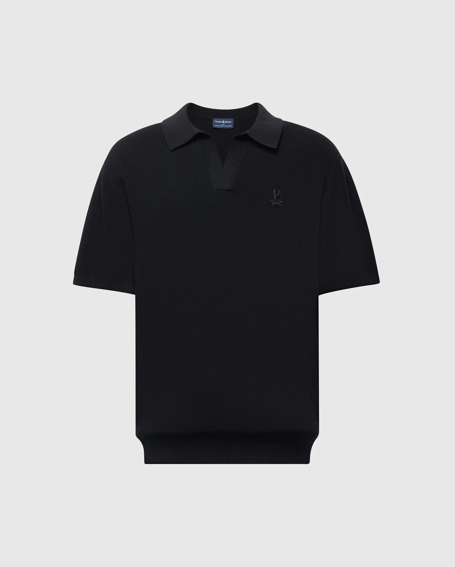 The Psycho Bunny MENS LEETON JOHNNY COLLAR KNIT POLO (B6E562F200) is a black, short-sleeve polo made from 100% cotton, featuring a subtle Bunny logo on the chest, dark collar, and breathable classic design against a light gray background.