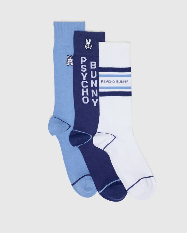 The Psycho Bunny MENS 3 PACK DRESS SOCK - B6F504F200 includes blue, navy, and white crew socks in a Pima cotton blend, each with branded bunny logos and stripe patterns, displayed side by side on a light background.