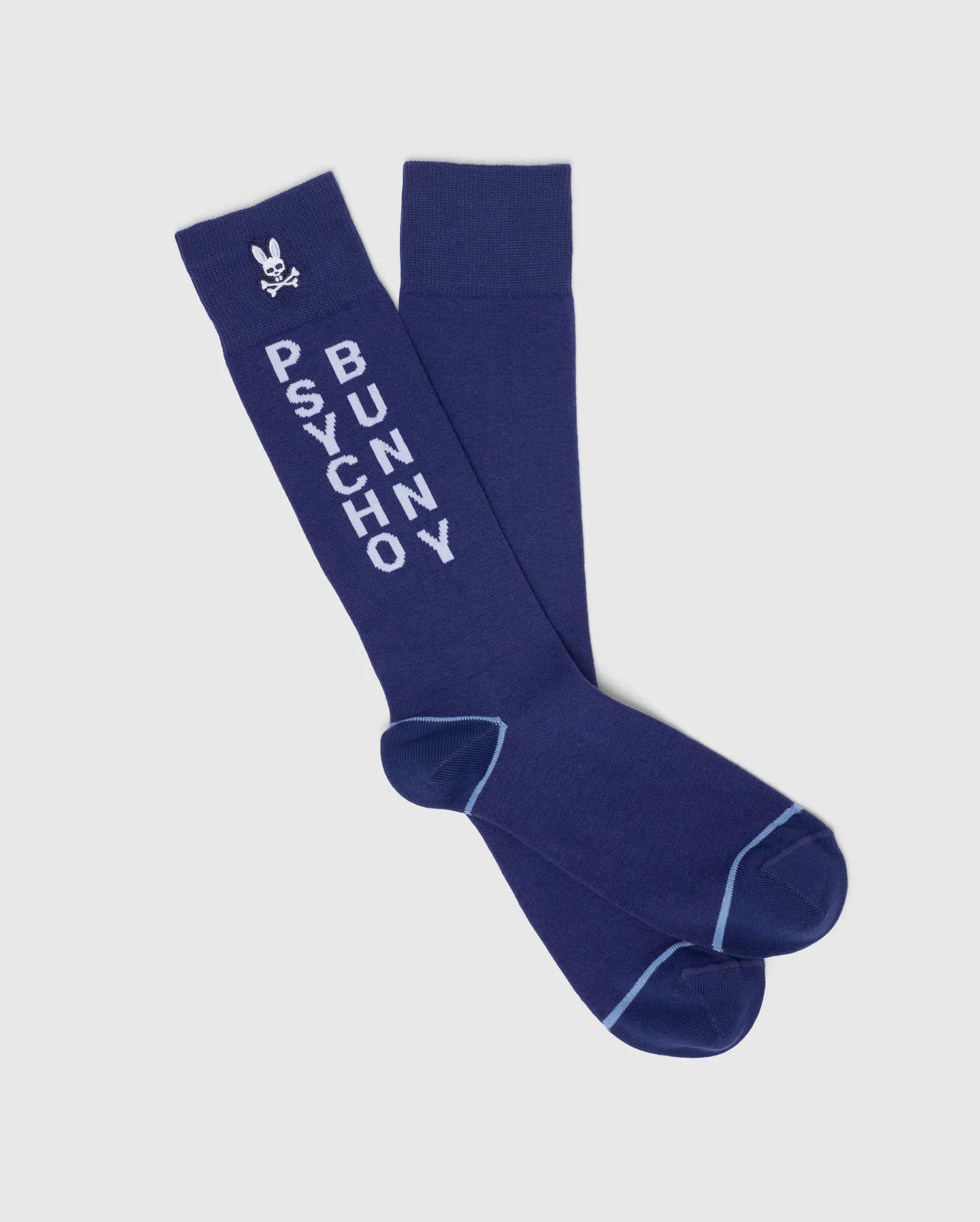 The Psycho Bunny MENS 3 PACK DRESS SOCK - B6F504F200 are blue knee-high dress socks in a soft Pima cotton blend, featuring “PSYCHO BUNNY” and a bunny logo with light blue trim at the toes and heels for added style.