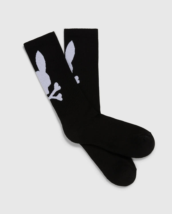 The Psycho Bunny MENS 3 PACK SPORT SOCK - B6F997D200 includes three pairs of black knee-high sport socks made from luxurious Peruvian pima cotton. These socks feature a distinctive white design that showcases a stylized skull and crossbones, with the skull cleverly shaped like a rabbit head. The socks are carefully arranged side by side on a simple gray background.