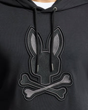 The Psycho Bunny Men's New Castle Embroidered French Terry Hoodie features a rabbit's head above crossed bones on black fabric. It includes black drawstrings, capturing New Castle's edgy style.