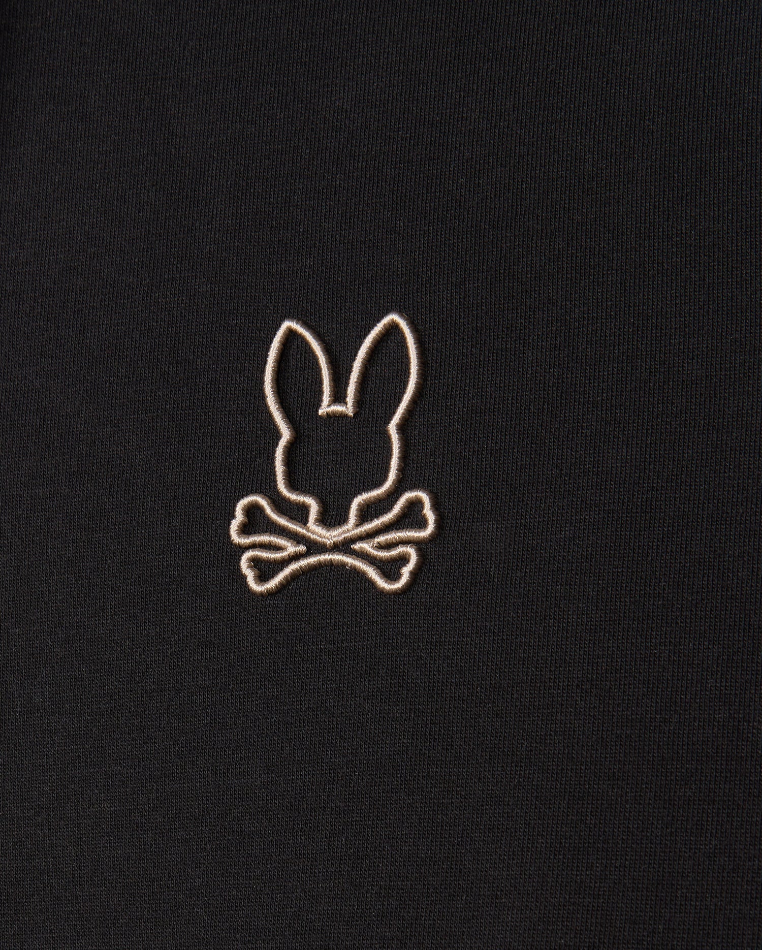 The Psycho Bunny MENS JAMES PREMIUM HOODIE - B6H789D200 features a black premium jersey fabric adorned with an embroidered design of a bunny head above two crossed bones in white stitching.