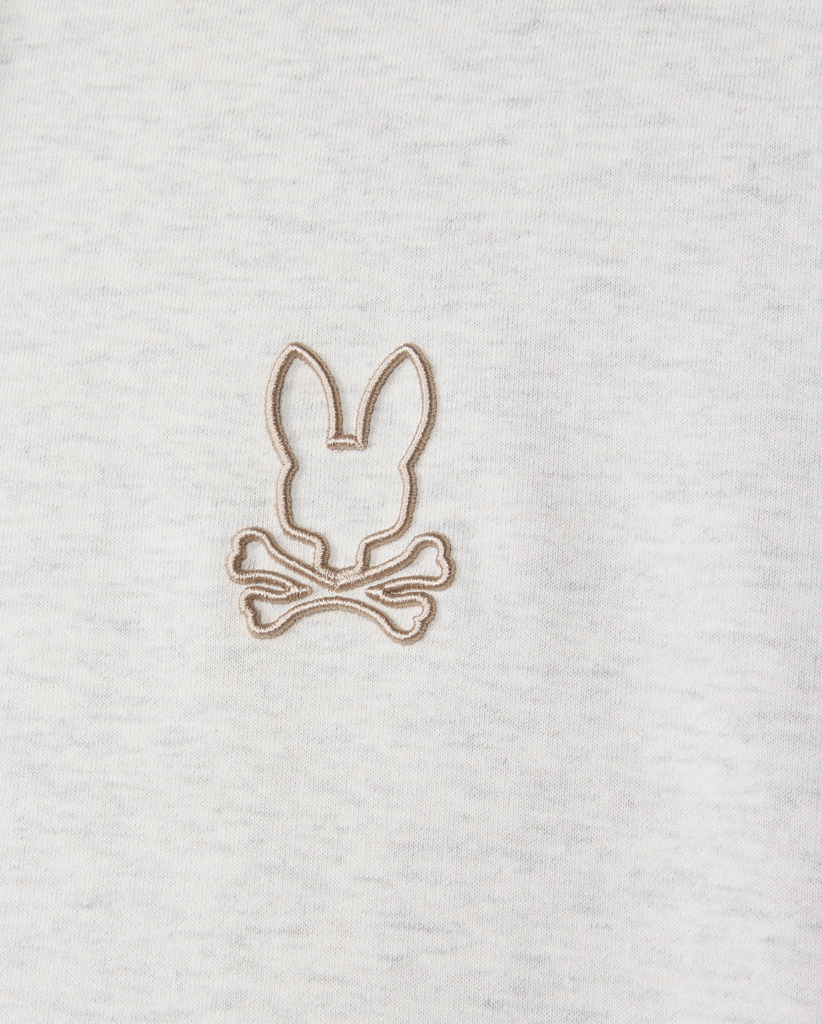 A close-up of the MENS JAMES PREMIUM HOODIE - B6H789D200 by Psycho Bunny features a gray fleece with a simple brown embroidered design of a bunny's head above crossed bones, offering a playful twist on the classic skull and crossbones motif.
