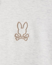 A close-up of the MENS JAMES PREMIUM HOODIE - B6H789D200 by Psycho Bunny features a gray fleece with a simple brown embroidered design of a bunny's head above crossed bones, offering a playful twist on the classic skull and crossbones motif.