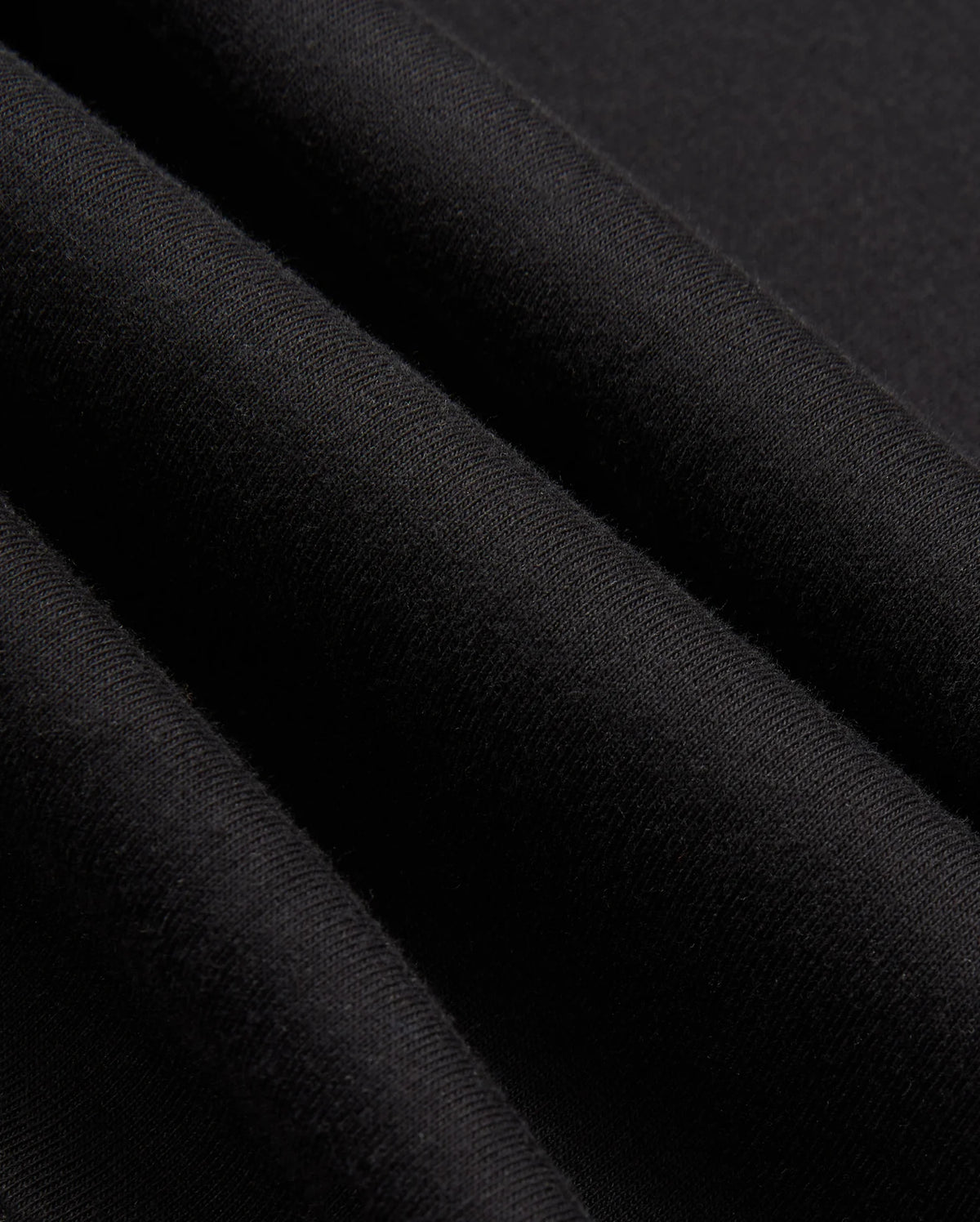 Close-up of black fabric revealing its woven texture and soft sheen, evocative of a high-quality jersey. The material appears smooth and slightly folded, suggesting the stylish warmth you'd expect from the Psycho Bunny Mens James Premium Zip Hoodie - B6H793D200.
